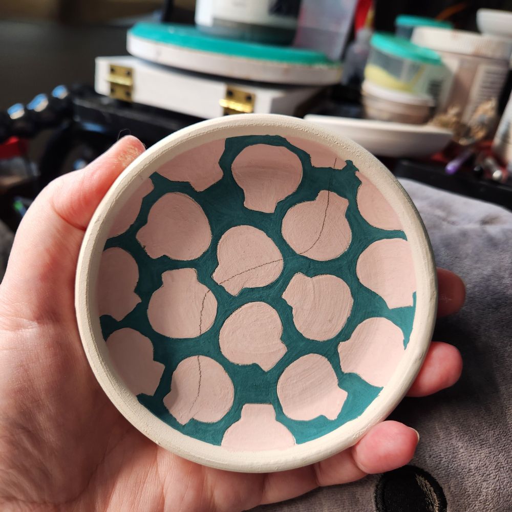 Halfway painted ceramic dish with turquoise background and pink skulls