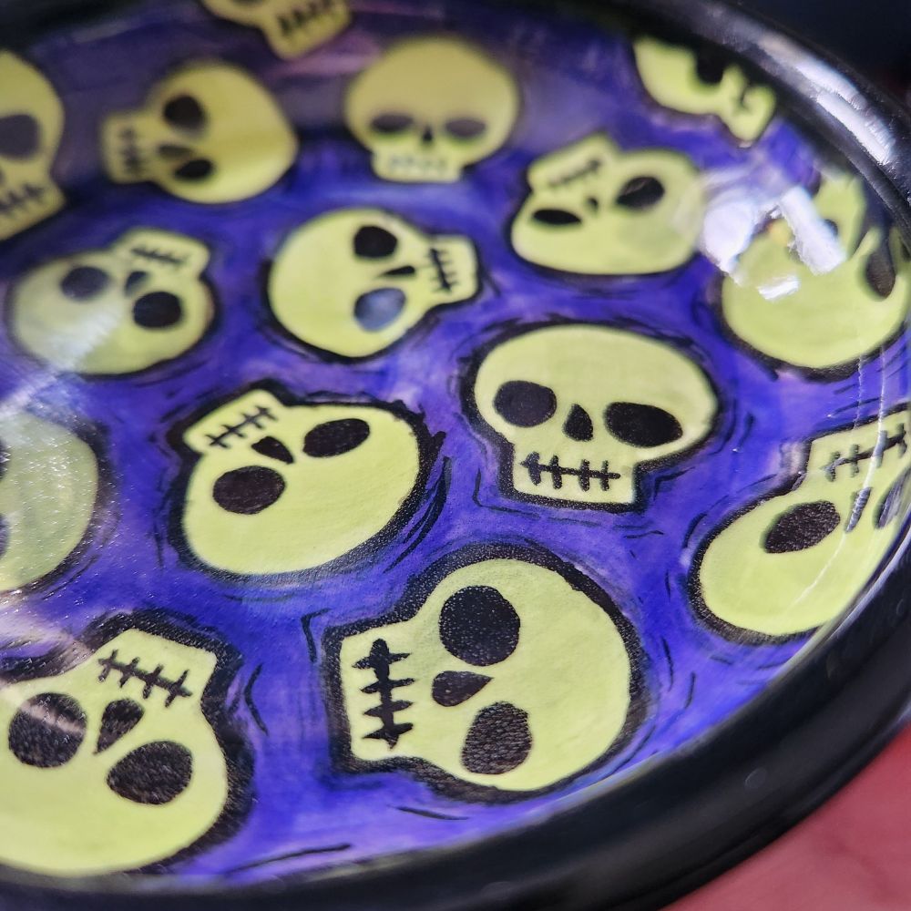 Detail view of small fish with green skulls & purple background with black rim