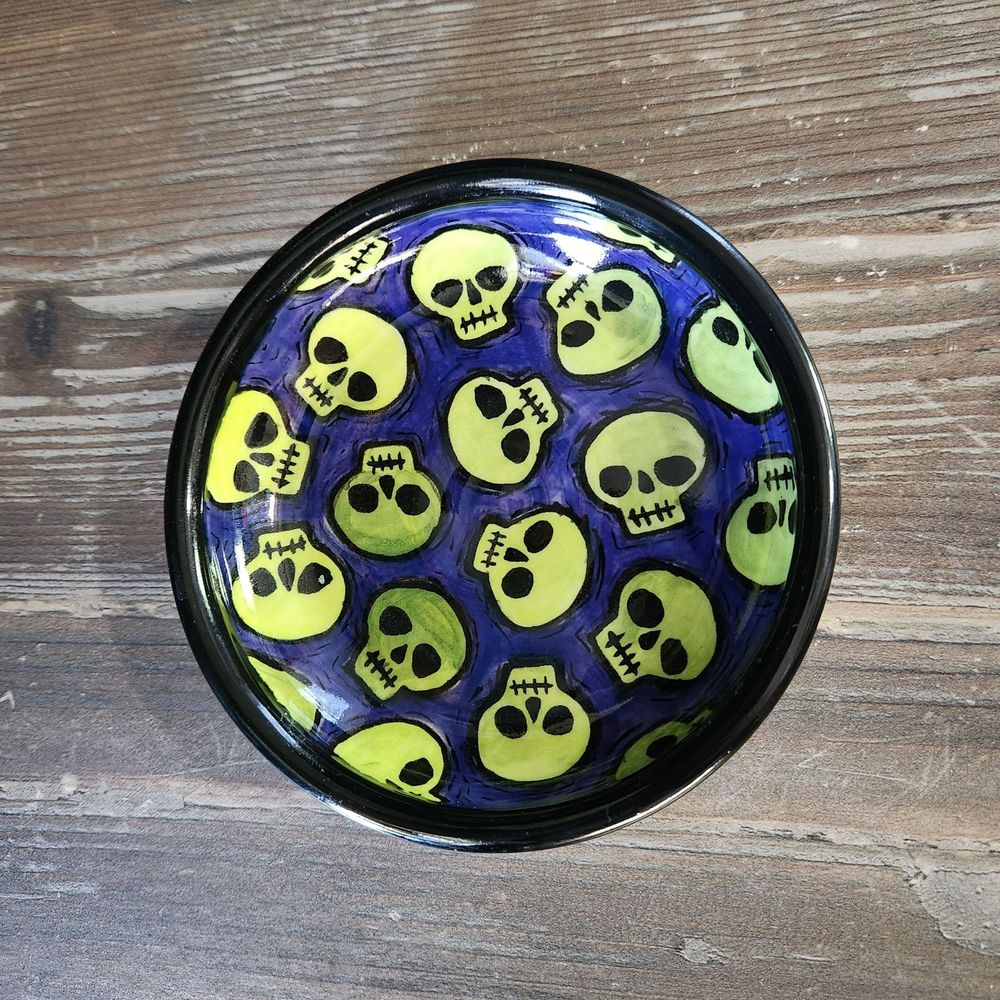 Full view of small fish with green skulls & purple background with black rim