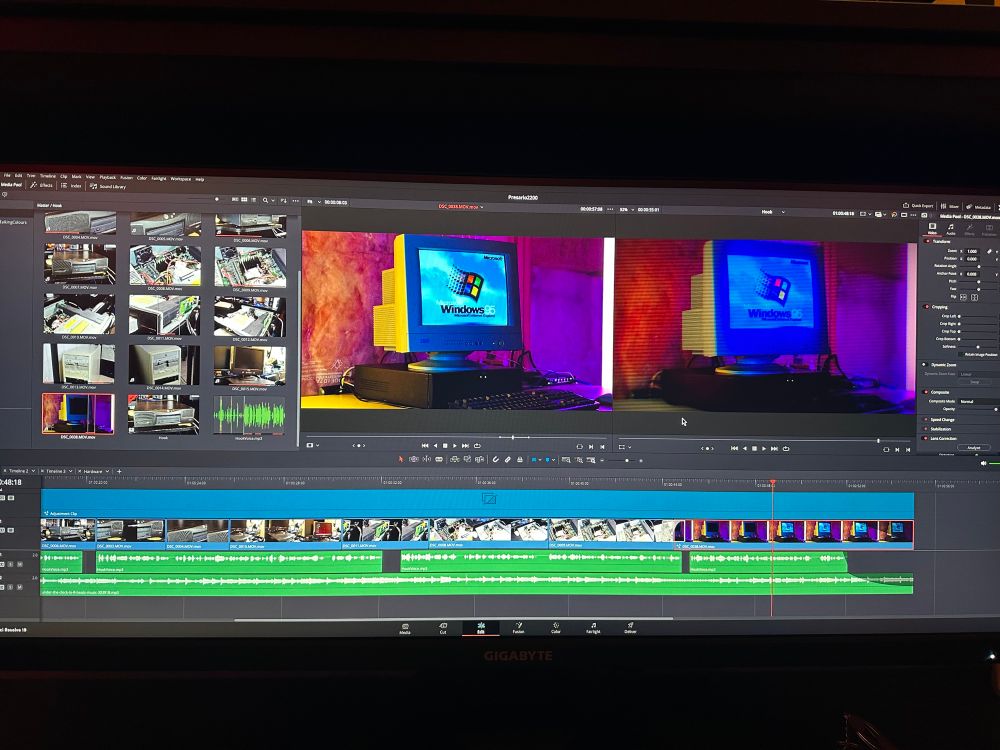A photo of an ultrawide monitor showing a video project in a video editor called DaVinci Resolve. There are a few video, audio, and effect tracks in the timeline, and the project monitors show a shot of a vintage computer setup with a beige CRT showing the Windows 95 boot screen. The shots are stylized with colourful warm, blue, and purple lighting, and the viewer on the right shows several effects applied, such as blooms, blur, scanlines, saturation, and rotoscoped areas for selective colour correction.