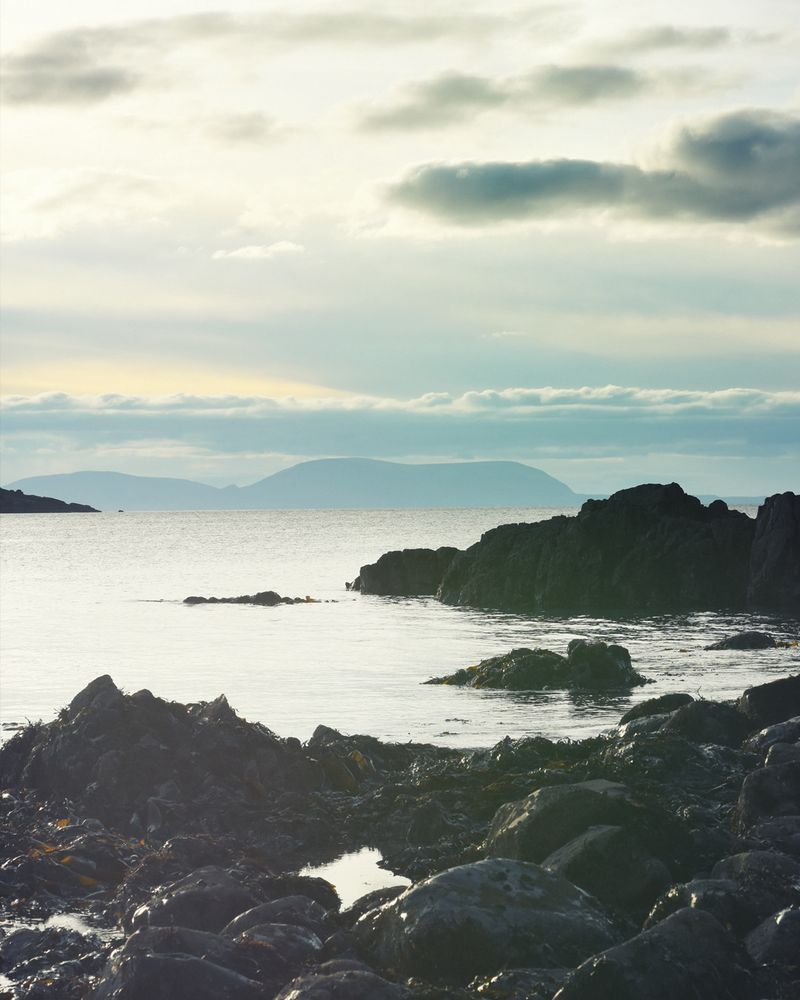 Coastline scene in NW Scotland. Foreground rocks and seaweed looking across the sea to Skye.