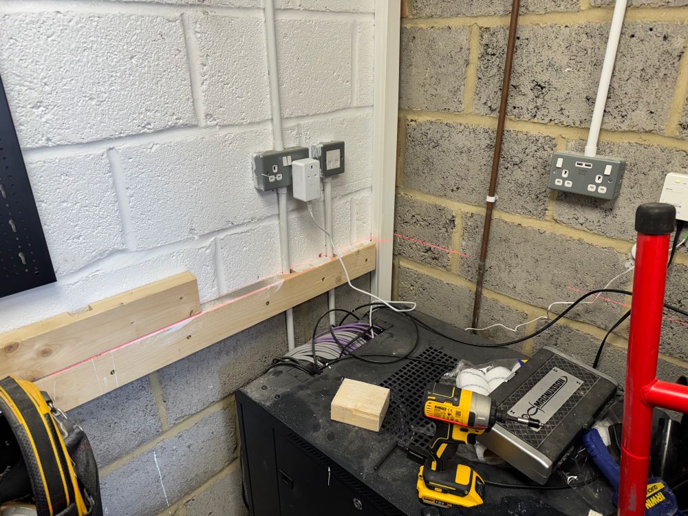 Using a laser level to make sure the buttons I’m fixing to my garage wall are level.