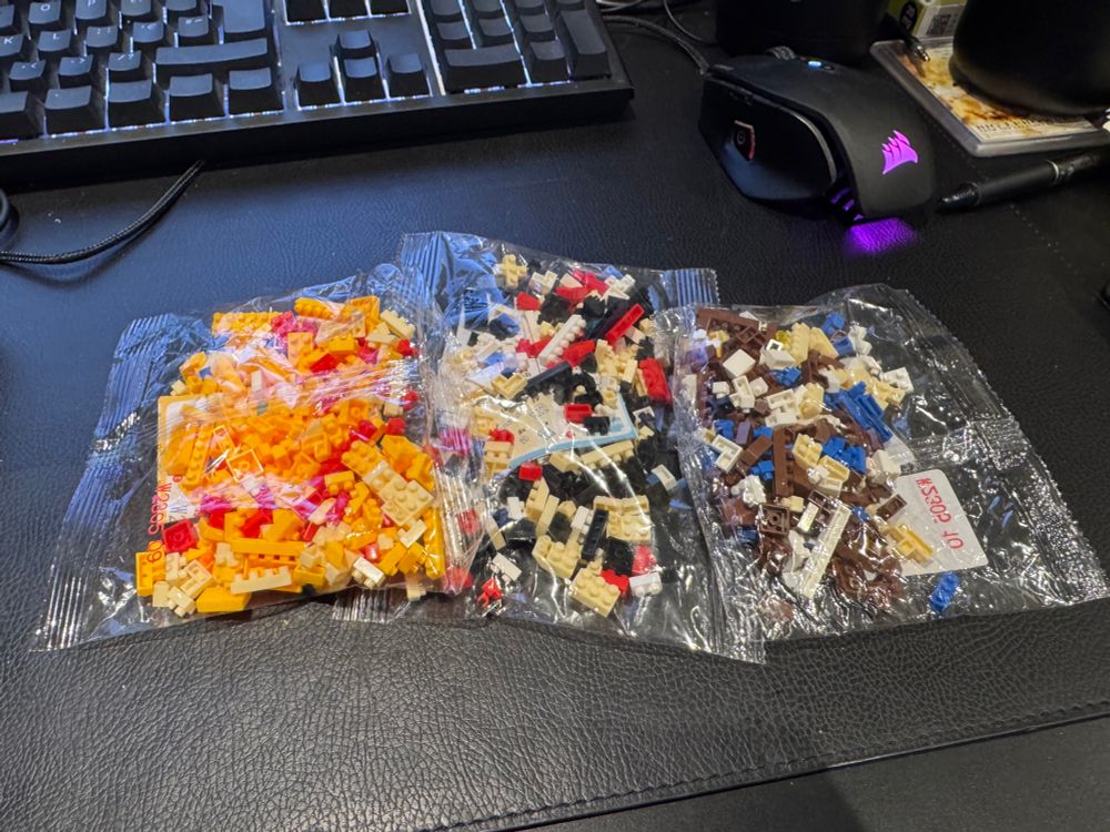 Three bags of tiny fake Lego pieces. One is red, yellow and pale yellow, one is white, black, red and pale yellow and the other is blue, white, brown, yellow and pale yellow. 