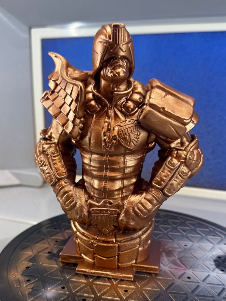 3D printed bust of Judge Dredd sprayed metallic copper. 
