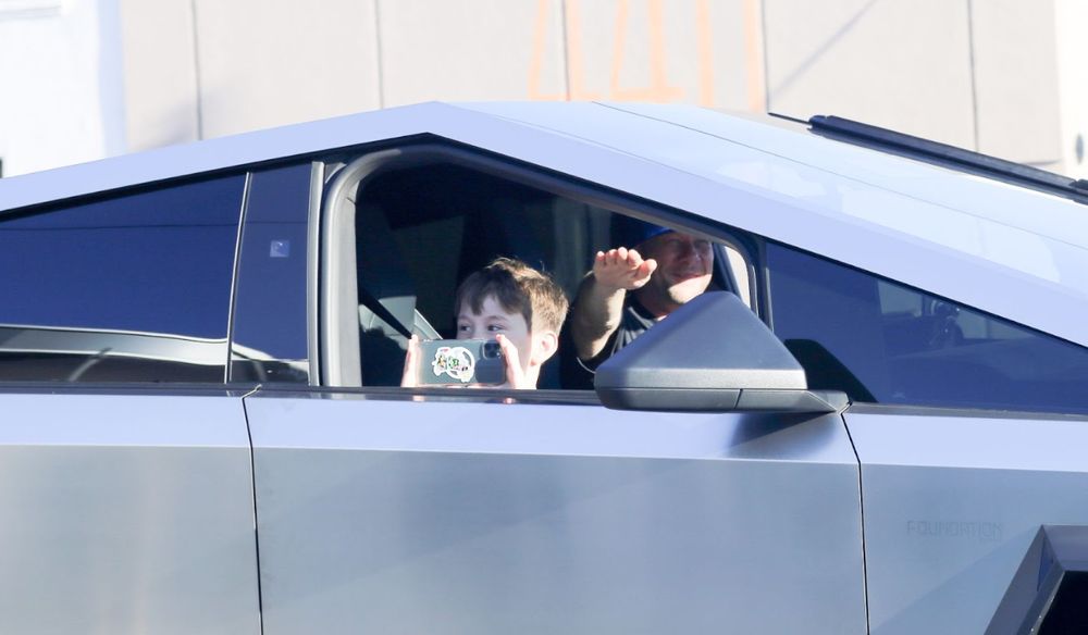 Man giving a natzi salute with his sone in the car taking pictures of the protesters