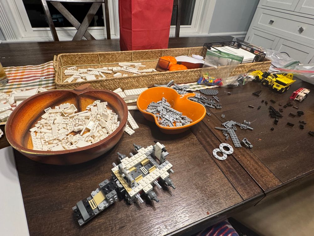 A small Lego construction that will be the interior of the shuttle with many, many pieces on the table waiting to be added 