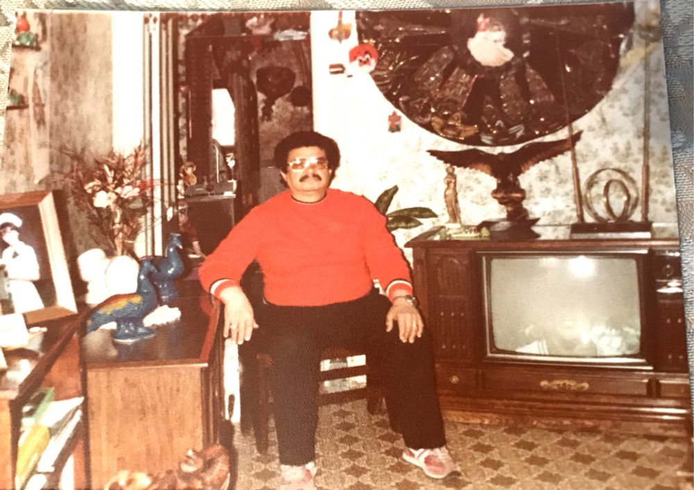 My dad sitting in a chair with a red sweater in our living room 