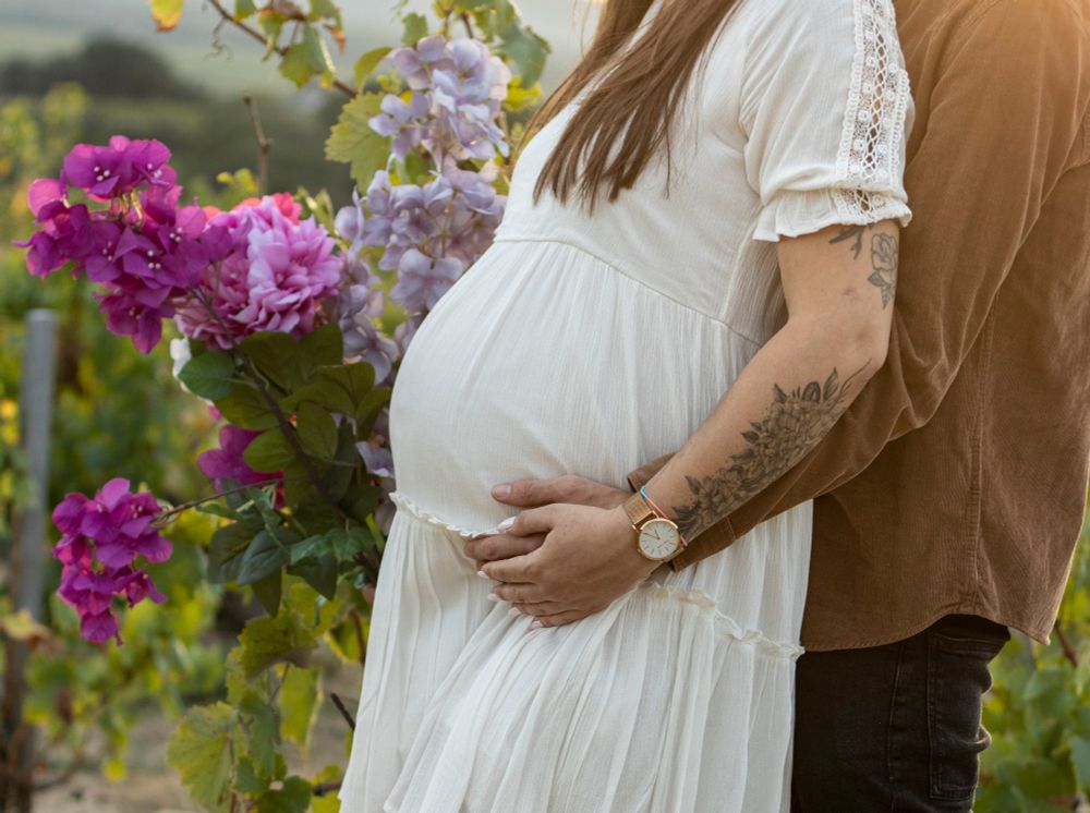 Photo d'une femme enceinte en robe blanche dans les vignes