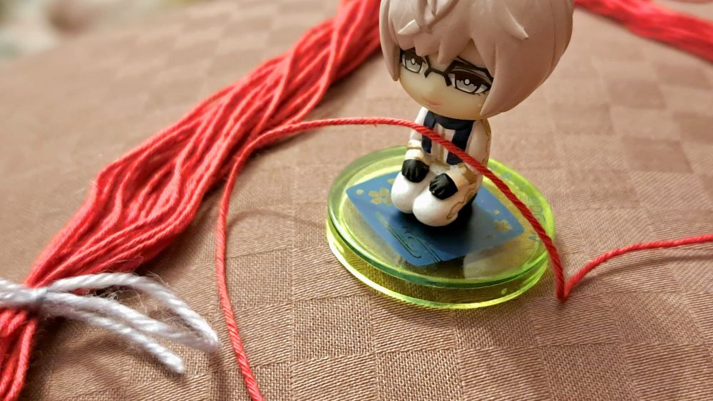 刀剣男士・亀甲貞宗の小さいフィギュアと赤い刺し子糸の束