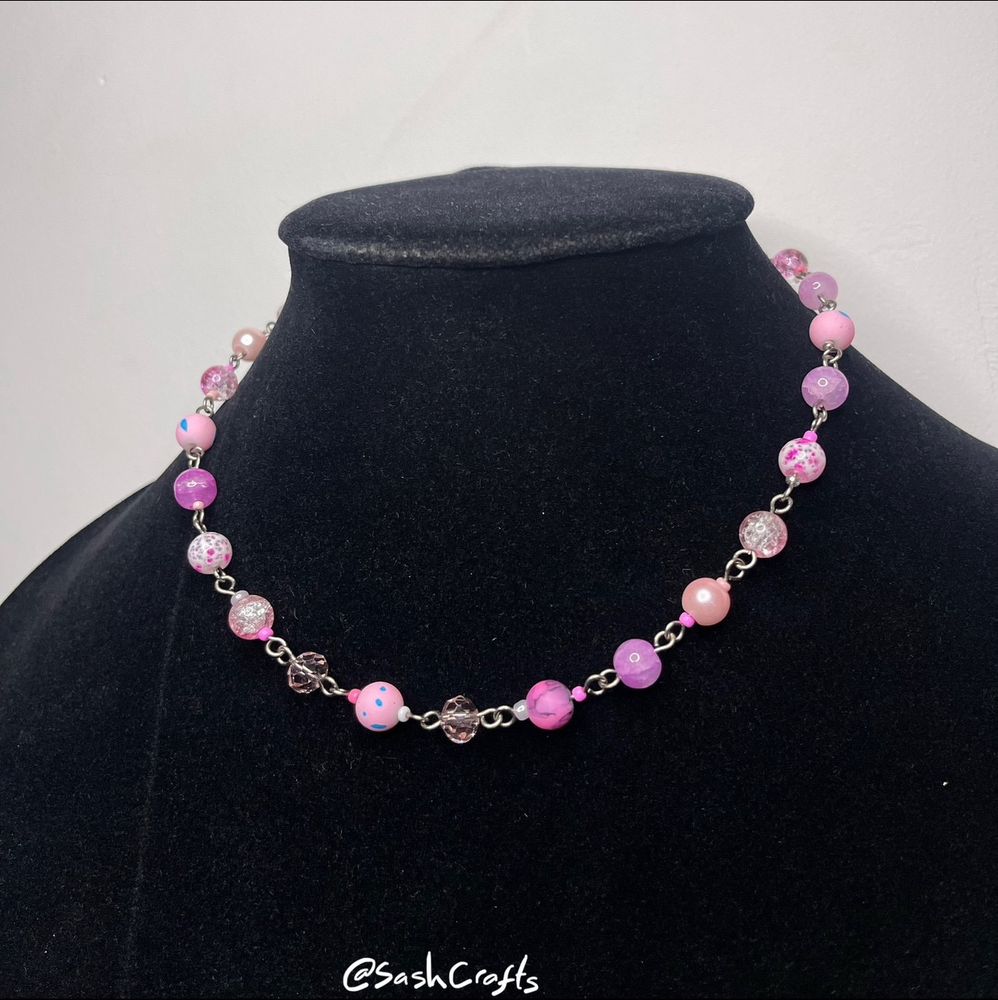 a beautiful pink necklace on a black velvet bust made with a variety of pink beads. they are mostly 8mm round beads but some are sandwiched between 3/4mm beads of various textures and shades of pink. the beads selected randomly whilst creating. they are beautiful! 