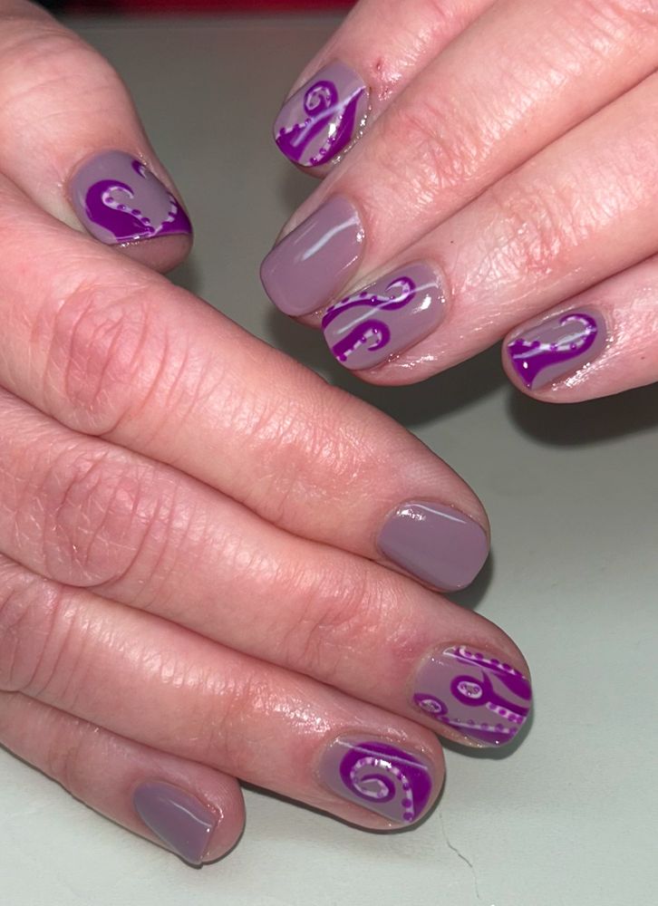 Close up photo of my fingers and nails. The nails are a pale purple color with bright purple octopus tentacles painted on some of them