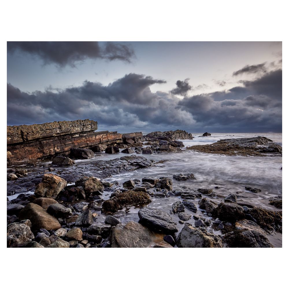 Rocky shoreline with rough sea and stormy clouds