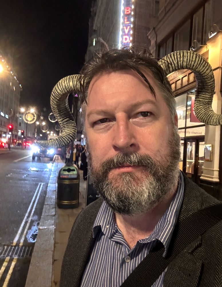 Photo of a bearded white man who’s clearly had a few drinks and old enough to know better wearing ram horns