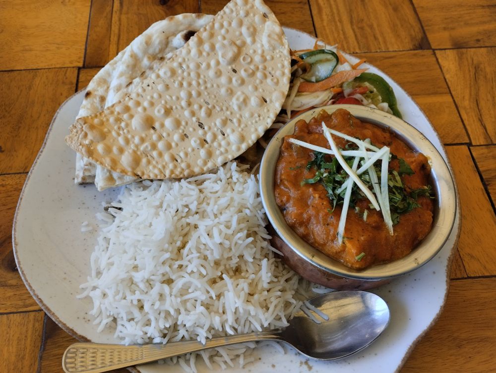 A plate of Indian food on a wooden table that looks like a wooden floor 