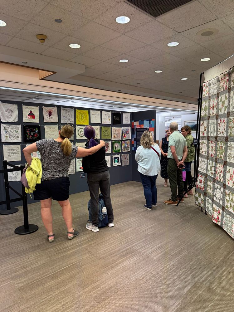People looking at a wall of fiber art