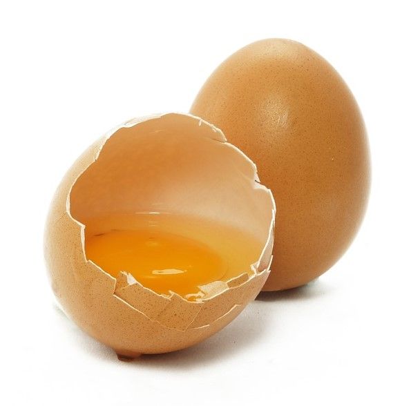 La imagen muestra un huevo de gallina entero junto a la cáscara de otro que muestra en su interior la yema.