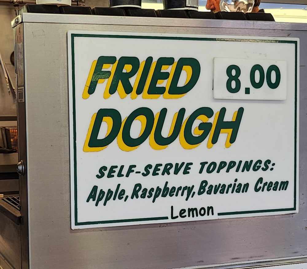 A sign reading Fried Dough 8.00

"Self-serve Toppings:
Apple, raspberry, Bavarian cream, lemon"