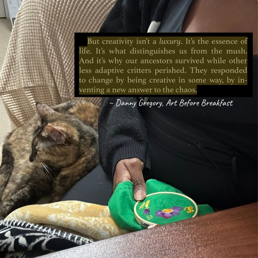 A Black woman cuddled with her tortoiseshell cat and embroidering a flower onto fabric. There is a screenshot of a quote from “Art Before Breakfast” by Danny Gregory at the top of the image. It says, “But creativity isn’t a *luxury*. It’s the essence of life. It’s what distinguishes us from the mush. And it’s why ancestors survived while other less adaptive critters perished. They responded to change by being creative in some way, by inventing a new answer to the chaos.”