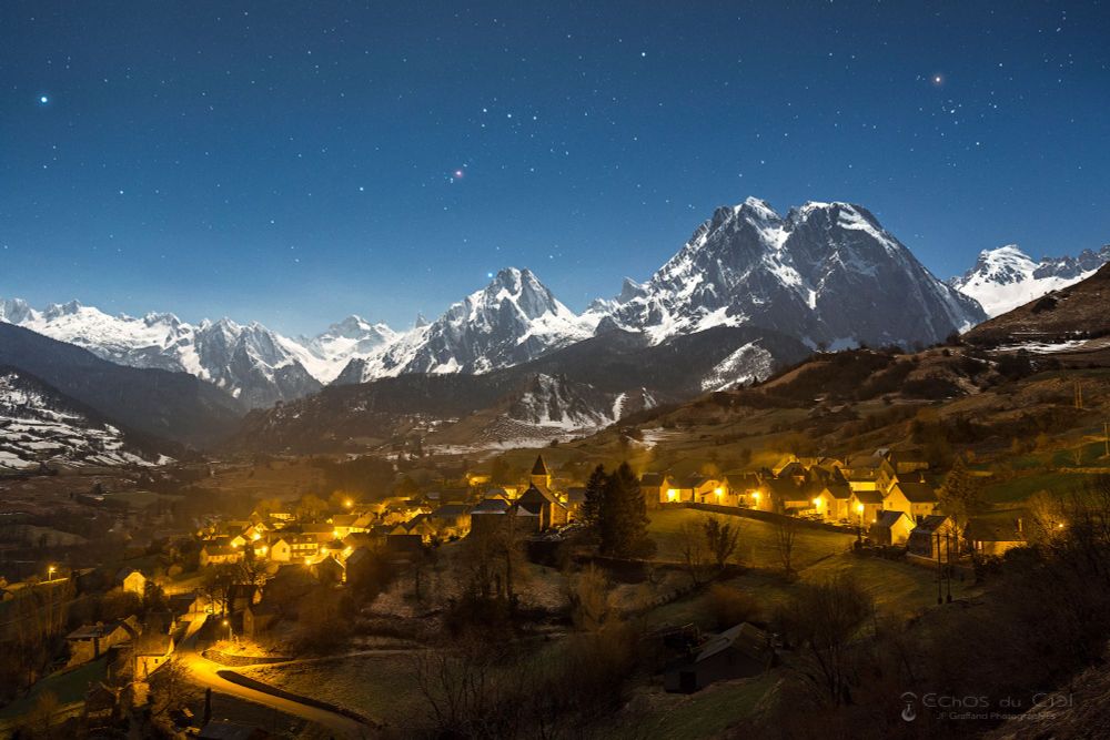 (english below)
Nuit d’hiver au clair de lune illuminant les imposantes montagnes du Cirque de Lescun. Dans le ciel, on retrouve les constellations emblématiques du ciel d’hiver, avec de gauche à droite : l’étoile Sirius, la plus brillante du ciel nocturne ; puis Orion vers le centre, reconnaissable à ses trois étoiles proches et alignées au milieu de la constellation, et avec en-dessous la petite tache rosée de la Nébuleuse d’Orion ; et vers la droite l’étoile Aldébaran et la tête du Taureau en forme de V.

Lescun by moonlight
A winter's night with moonlight illuminating the imposing mountains of the Cirque de Lescun. From left to right: the star Sirius, the brightest in the night sky; then Orion towards the center, recognizable by its three stars close together and aligned in the middle of the constellation, with the small pinkish spot of the Orion Nebula below; and to the right the star Aldebaran and the V-shaped head of Taurus.
