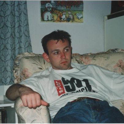 Me at 17 years old, in loose-fit jeans and a Levi's 501 t-shirt looking strangely tanned, while sitting on my Mum's floral chair in London.