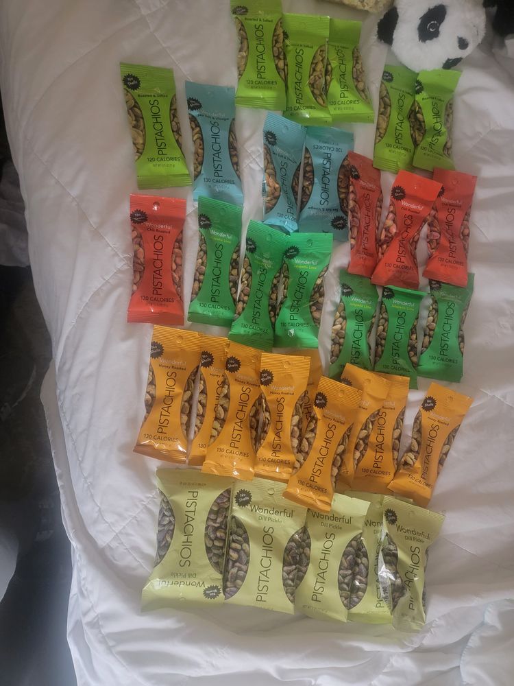 various flavors of pistachios haphazardly spread out onto a bed. 30~ish in total