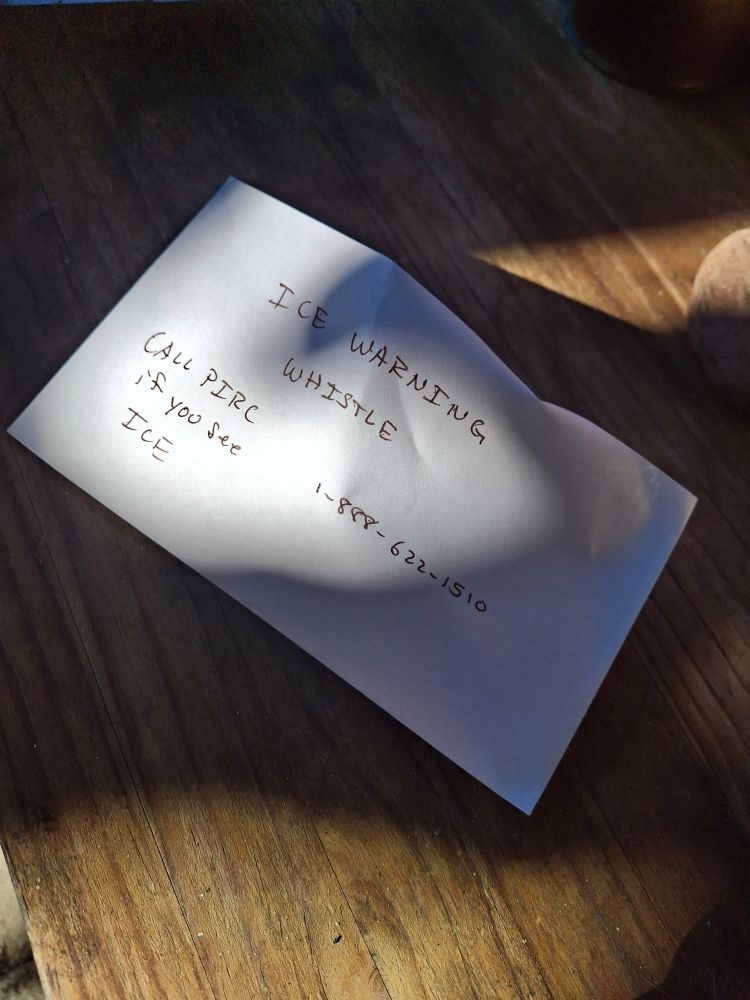 Envelope bulging from a small object, labeled "ICE Warning Whistle" as well as an Immigration rights phone number. 