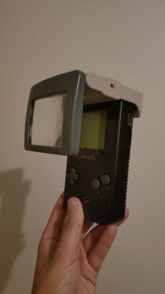 Photographie d'un GameBoy de couleur noire avec une loupe grossissante et qui permettait d'eclairer l'ecran pour jouer en voiture et dans le noir.
Cette console me fut offerte a Noël 1996 par ma mère. L'une de mes plus grande joie jusqu'à ce que j'ouvre le deuxième paquet et que je découvre qu'elle a acheté Tintin au Tibet.
Derniere fois que j'ai fait confiance a quelqu'un pour un cadeau de Noël