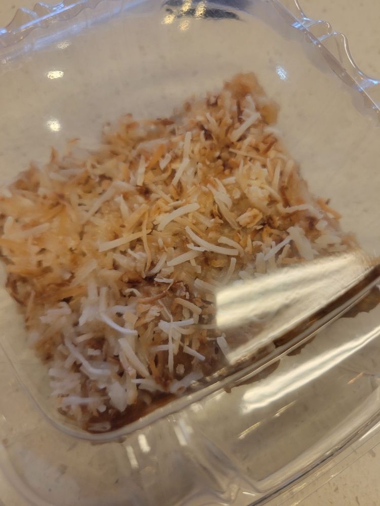 lemon bar with toasted coconut topping in a clear box
