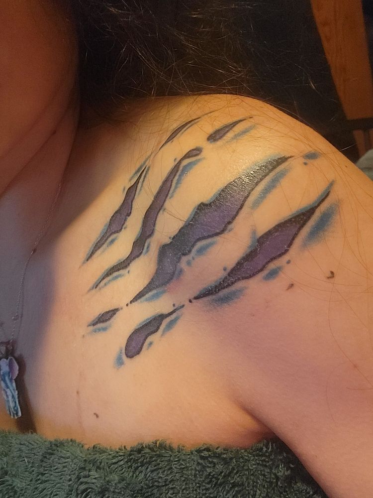 four dragon scratches across a shoulder in purple and black ink, with blue scaring around them
