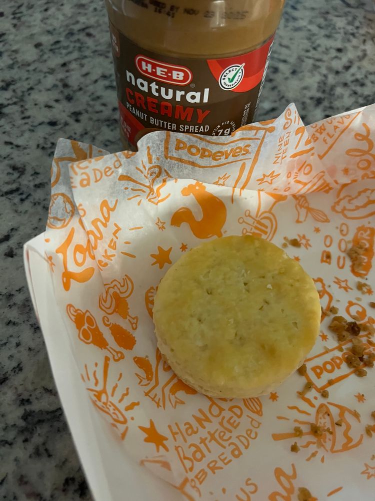 popeyes biscuit and a jar of peanut butter sitting on the countertop which could combine to create the driest thing ever and massive choking hazard 