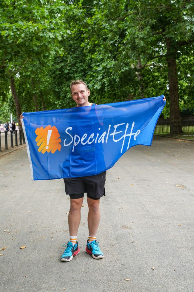 Photo of me holding a SpecialEffect banner before the London 10k 2025