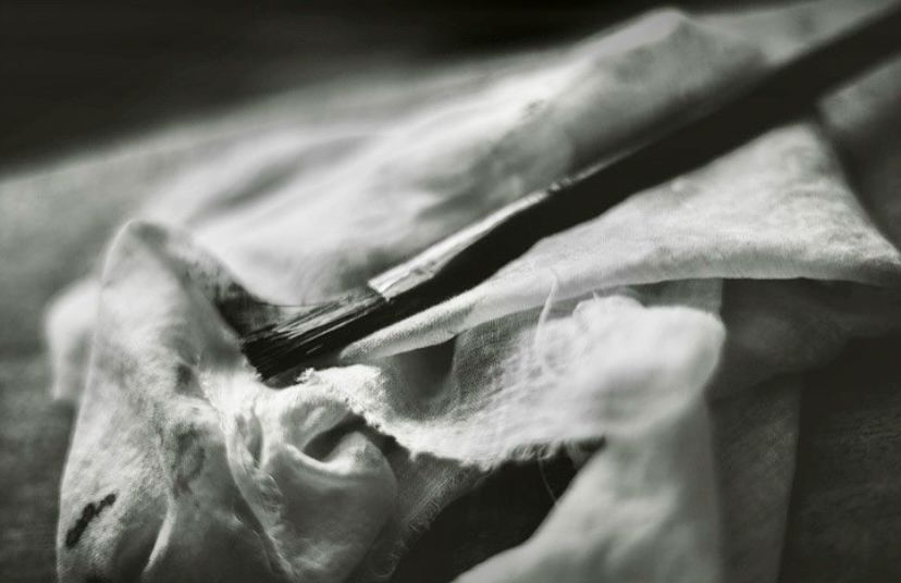 Black handled paintbrush against a white drop cloth. 
