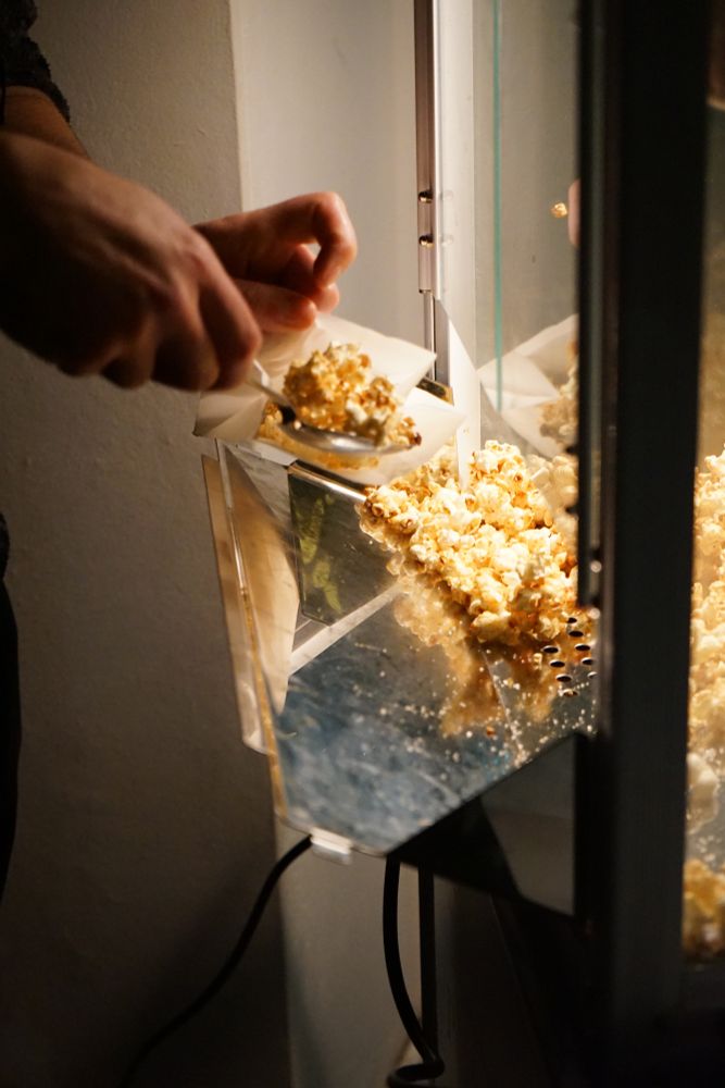 Das Bild zeigt, wie jemand Popcorn in eine Tüte packt.