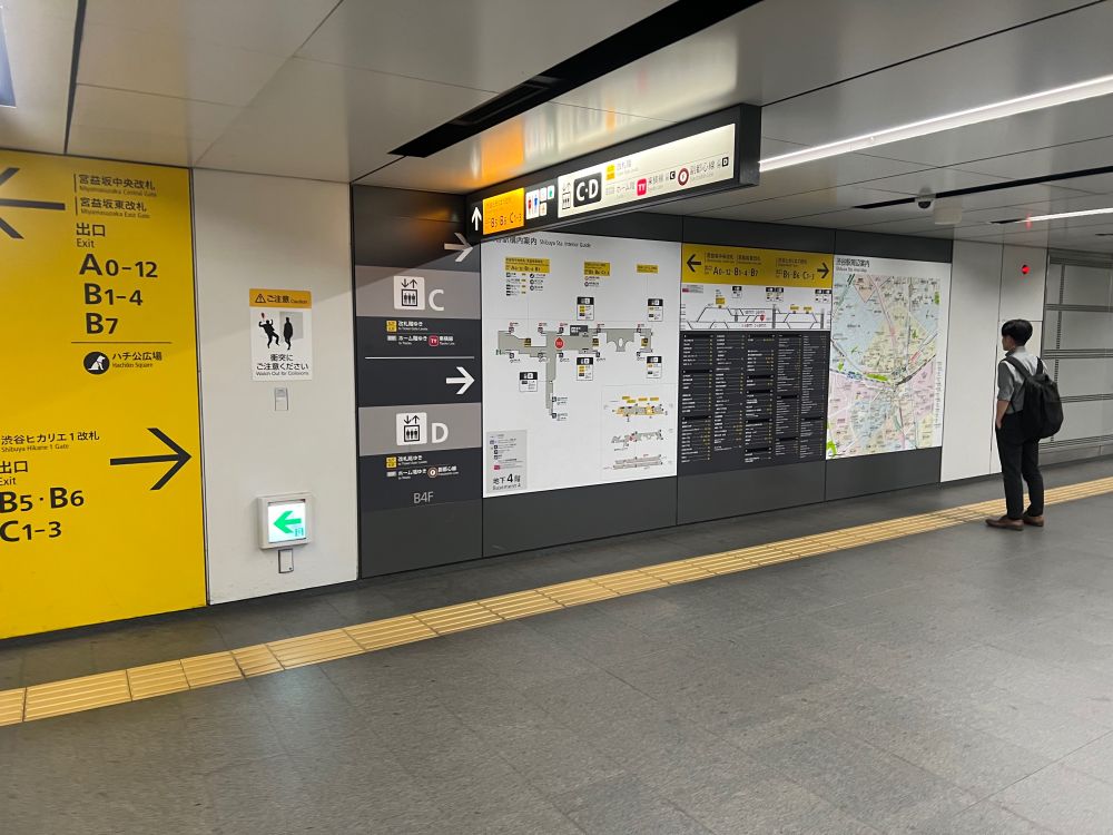 A wall with maps, guides, and arrows pointing to exits