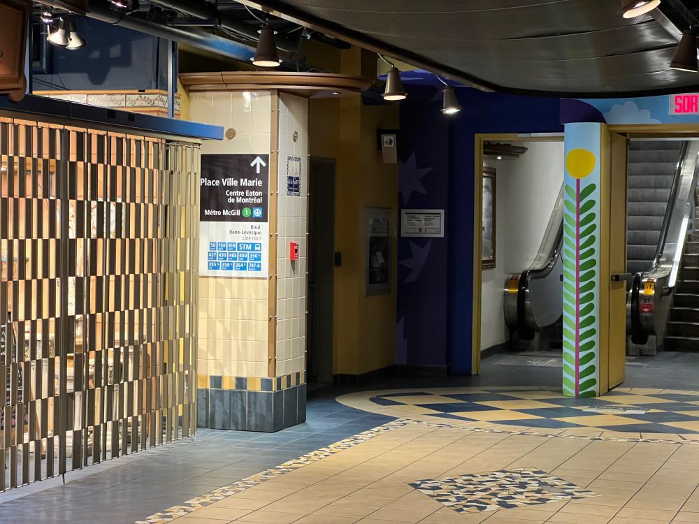 Large sign on tiled pillar, pointing to Place Ville Marie, Eaton Centre and connecting buses and local streets