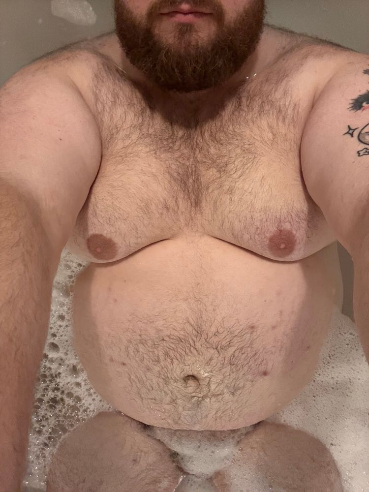 fuzz bear laying in a tub with bubbles covering crotch. 