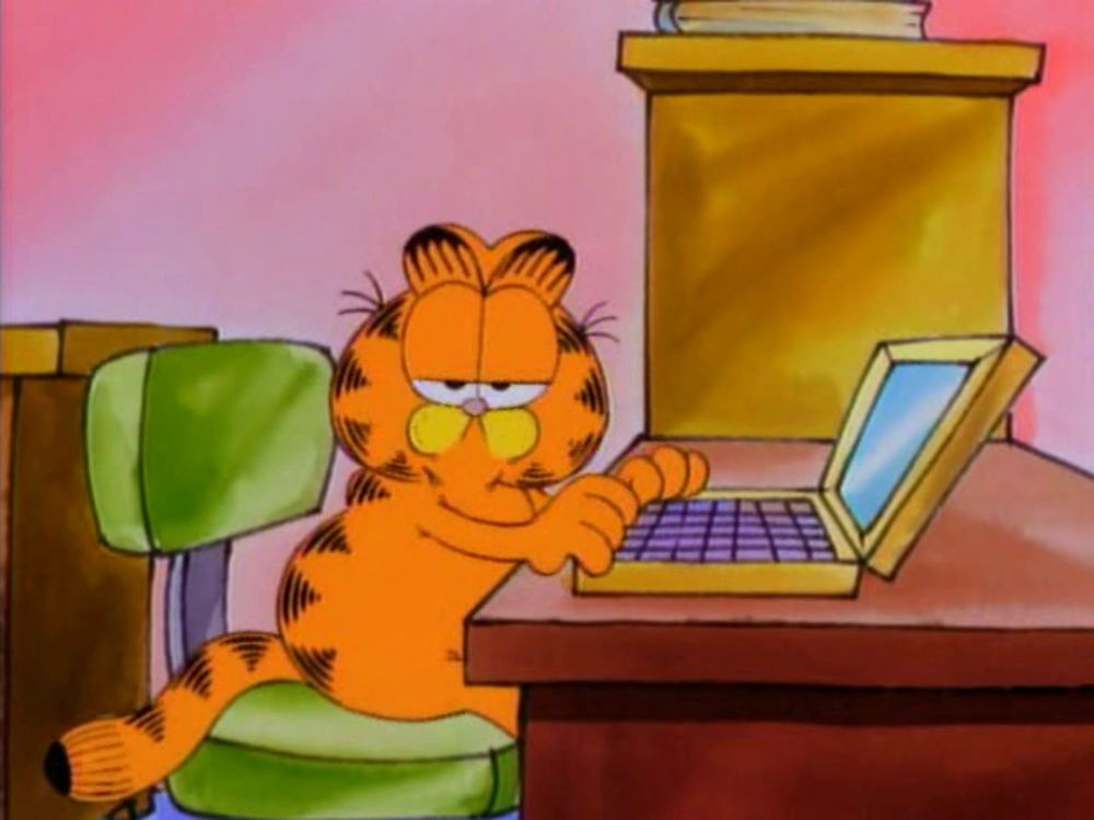 garfield sitting at a desk typing on a laptop