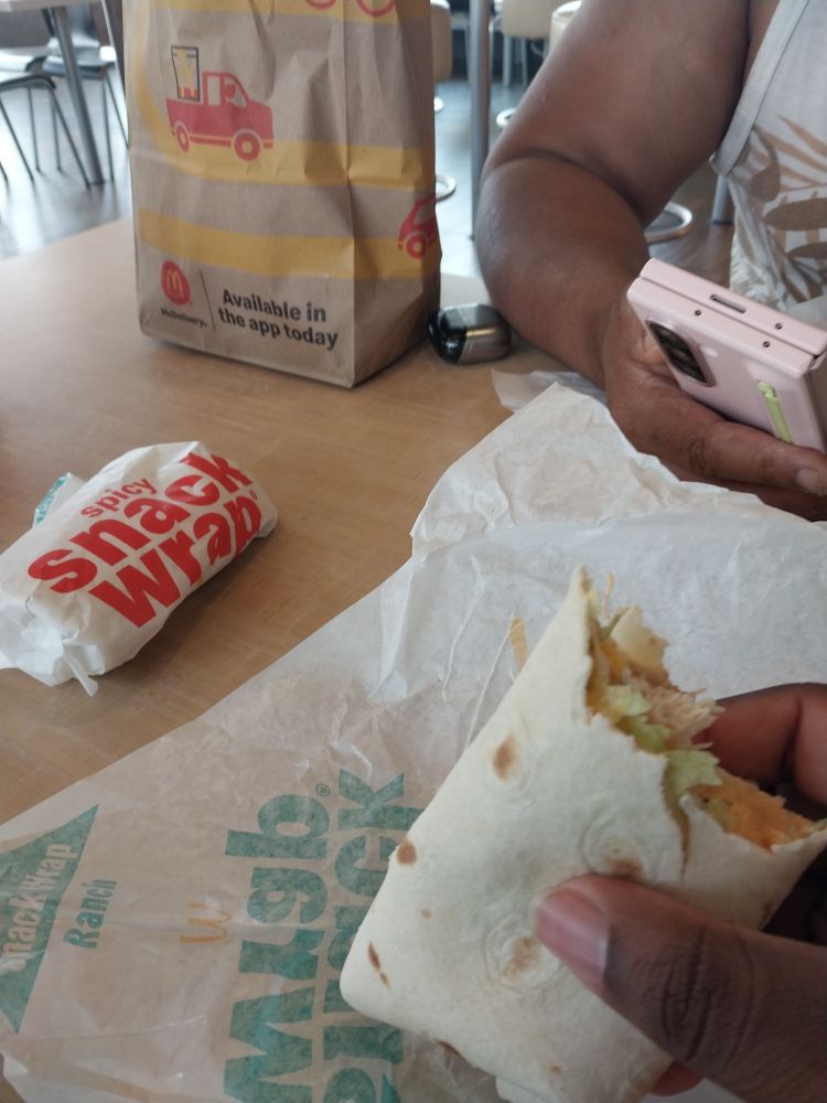 A photo of me holding half of a spicy Snack Wrap with another one off to the side waiting it's demise.