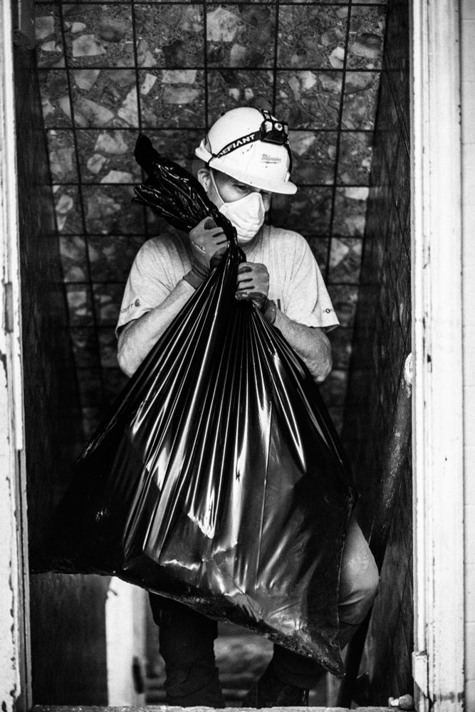 A man walks up a staircase in Milwaukee, WI carrying a large garbage bag full of debris. 