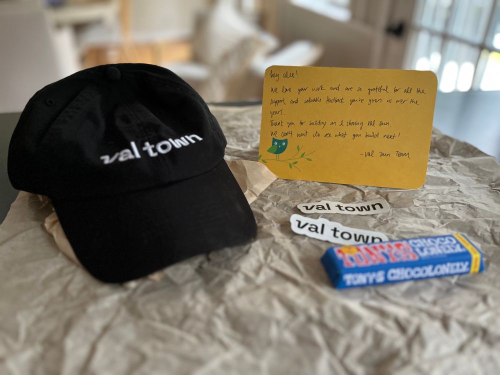 Swag from Val Town! A black cap with the Val town logo, a handwritten note from the team, 2 Val town stickers and a Tony’s Chocolonely chocolate bar!