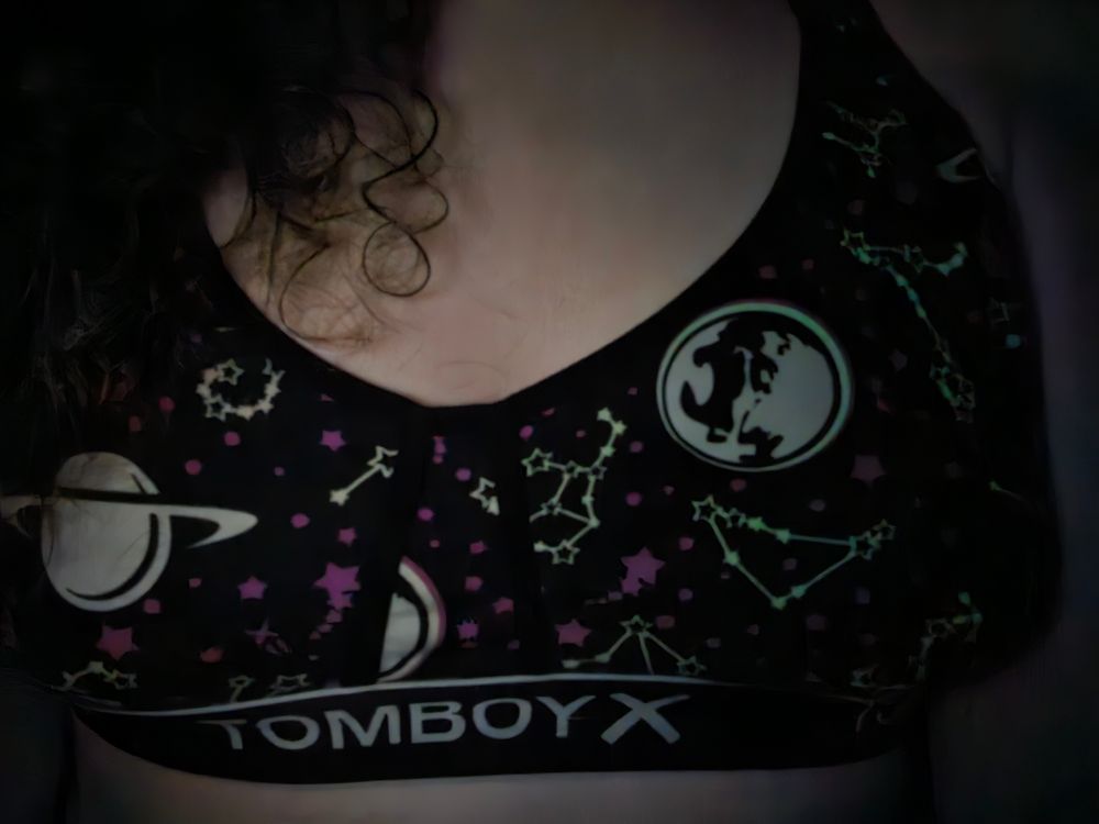Photo of my chest in my glow in the dark space pra. You can see the moon, Saturn, and various constellations which are flowing in the dark and the background color is a dark purple with some lighter purple background stars.