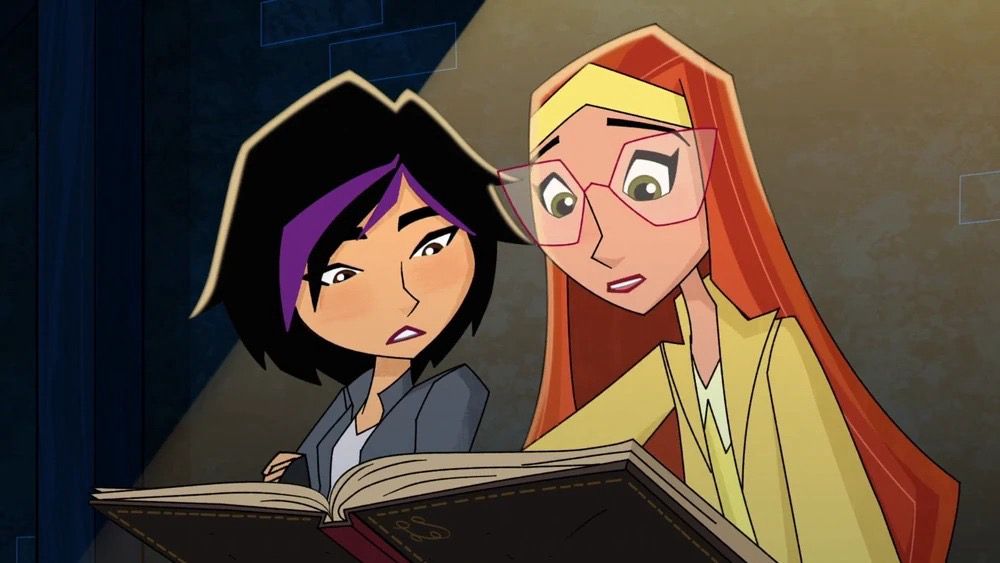 Go Go Tomago and Honey Lemon from Big Hero 6. Honey Lemon is to the right of the image in fully yellow attire - a yellow top with a very soft yellow collard shirt peaking beneath it, a yellow coat and a yellow headband. It compliments her long, straight orange hair well. She also wears thin pink cat eye glasses. She’s leaned over a brown leather bound book and is sitting next to Go Go Tomago who leans towards her over the book also. She’s in a light grey top with a darker grey coat like top layered with it. Her hair is short (above shoulder length) and black with three strips of purple around her fringe.