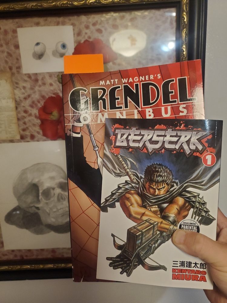 Berserk Vol 1 and Grendel Omnibus Vol 1 in front of a pencil drawing of a skull. 