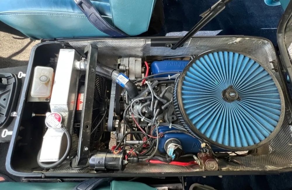 Open engine compartment in 1960s Ford Van for sale. Engine compartment is between the two front seats. 