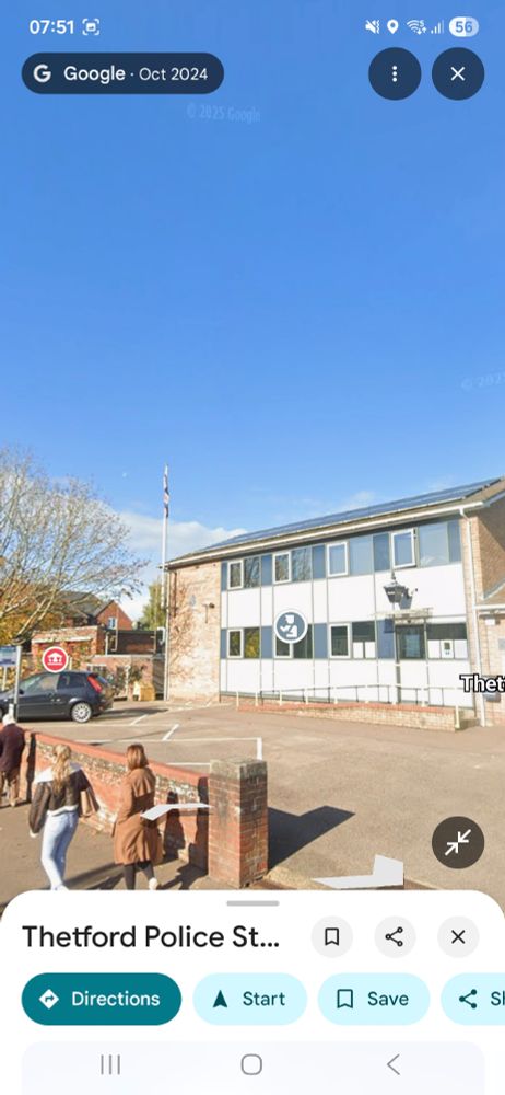 Google street view screenshot of Thetford Police Station, which is a drab 80s small town police station in yellow brick and white panels. In tje car park is a flagpole with a limp hanging union flag.