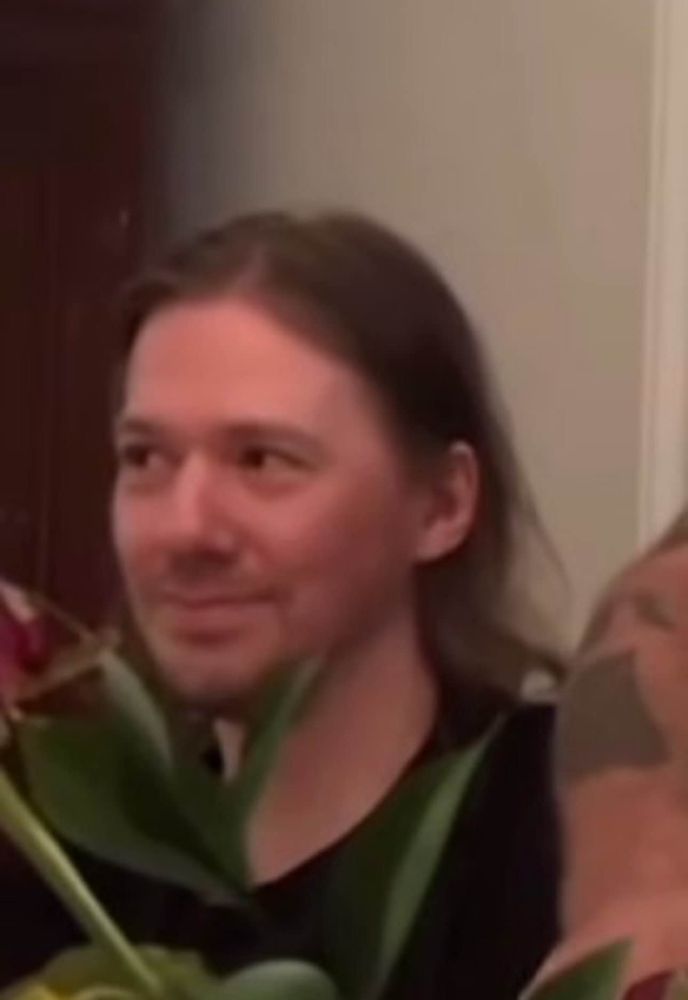 Tobias Forge between flowers, smiling devilishly 