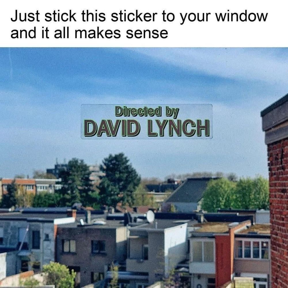 Top text: just stick this sticker to your window and it all makes sense.

Image: view out a window overlooking a residential area of townhouses and trees. A clear sticker on the window reads “directed by David Lynch” in the style of an opening credit.