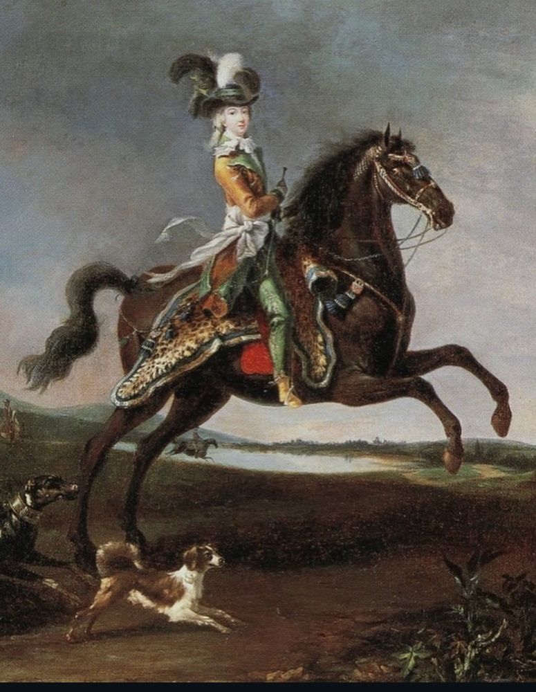 A portrait of Marie Antoinette riding a horse. 
The portrait is in a landscape style. Behind the horse and rider, is a brown open field and a pond. There is another horse and rider in the distance and another entering the picture.

 Marie Antoinette is wearing light green pants that are close fitted. She has on golden yellow short ankle boots, that are lighter than her bright gold jacket. The golden jacket has light green lapels and cuffs that match her pants.
Around her waist is a big white bow, tied so the ends stream behind her and this matches a ruffley lacey layer at her neck.
She wear her light colored hair (powdered white) tied back with a green ribbon - and to top it all off she has a wide brimmed light black but not grey hat with a light green ribbon around the…head part? And featuring three feathers (I think- it’s an oil painting …on the Internet!) two feather plumes are black and one is white.

A brown and white hunting dog runs along side her. The dog is white with a brown saddle, booty, and head. A black dog is entering the frame on the left.
The horse is dark brown and styled in a way that reflects the time- a narrow face and long legs.
Marie Antoinette sits on the horse -not side saddle but riding regular!
The saddle seems to be a leopard skin!