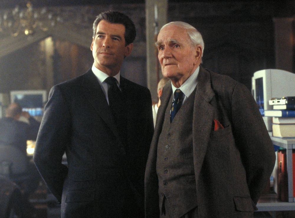 A picture of James Bond (Pierce Brosnan) and Q (Desmond Llewelyn) from the James Bond movie series, during a scene where Q is showing James some new gadgets.