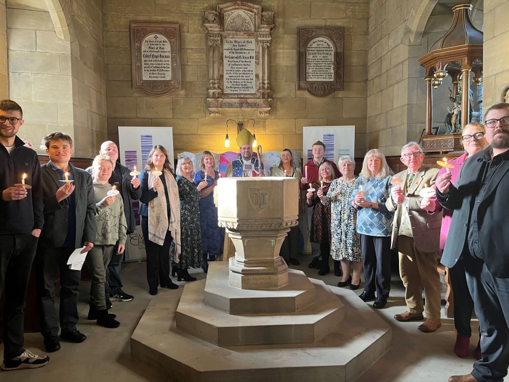 The baptism and confirmation candidates standing around the font holding candles, joined by me in robes